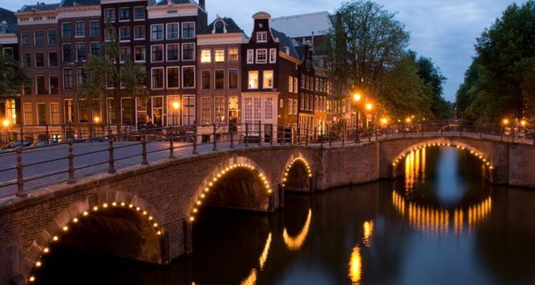 Lit canal bridges in a city at dusk.