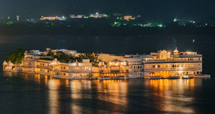 Un palacio brillantemente iluminado sobre el agua en la noche.