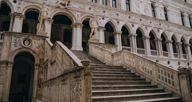 Sierlijke trappen in een historisch gebouw met gebeeldhouwde figuren.