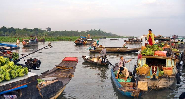 Marché flottant animé avec des bateaux transportant des fruits et des gens sur une rivière.