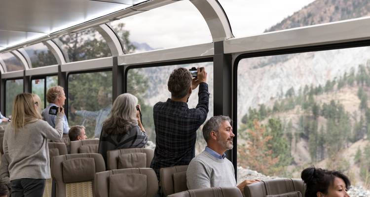 Les passagers se tiennent debout et prennent des photos à travers les fenêtres panoramiques à l'intérieur de la voiture à toit de verre du train.