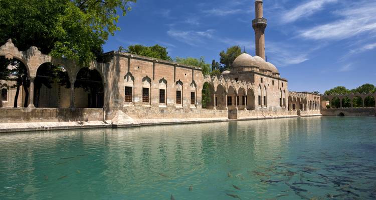 Edificio arquitectónico con minarete junto a un cuerpo de agua, probablemente en Şanlıurfa.