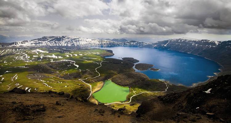Lago de cráter con paisaje dramático y nubes melancólicas.