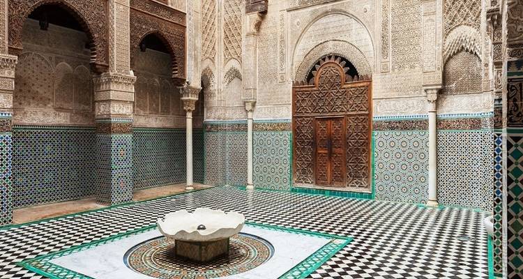 Islamic architectural courtyard with decorative tiles and a fountain.