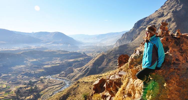 Personne contemplant un vaste paysage montagneux.