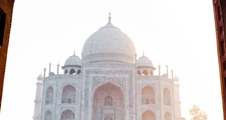 Silhouette rétroéclairée du dôme et des minarets du Taj Mahal brillant à travers la brume matinale.