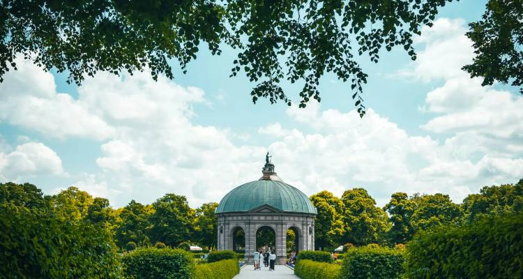 Les visiteurs apprécient un pavillon à dôme situé dans des jardins luxuriants lors d'une journée ensoleillée