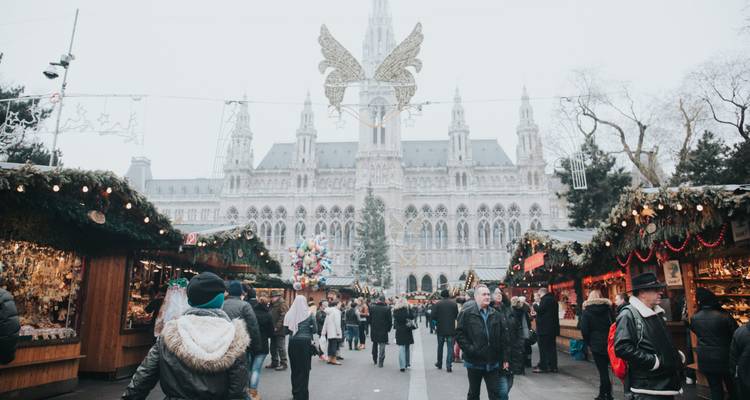Mercado navideño con un edificio gótico de fondo.