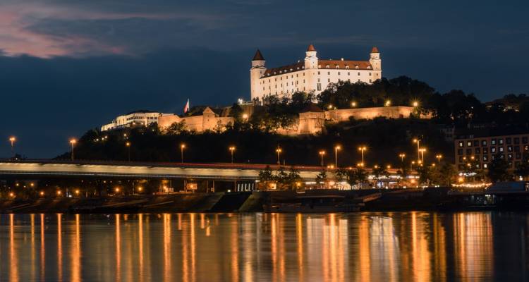 Castillo en una colina con vista a un río por la noche.