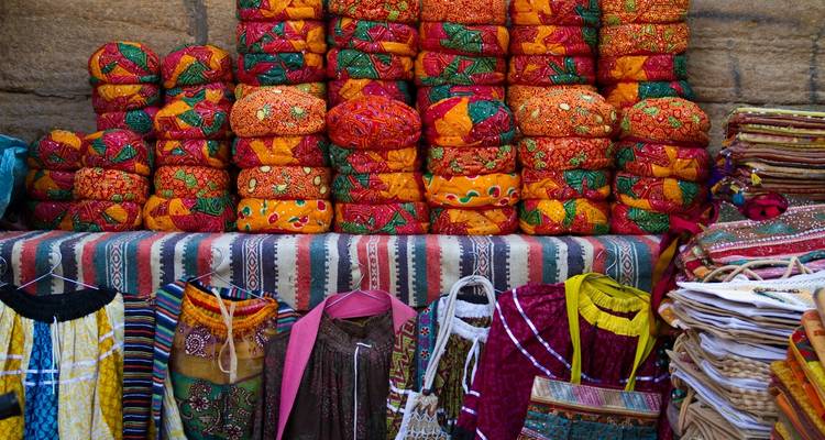 Colorful traditional textiles and garments displayed in a market.