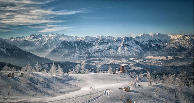 Vue étendue sur des montagnes enneigées avec une vallée et des forêts.