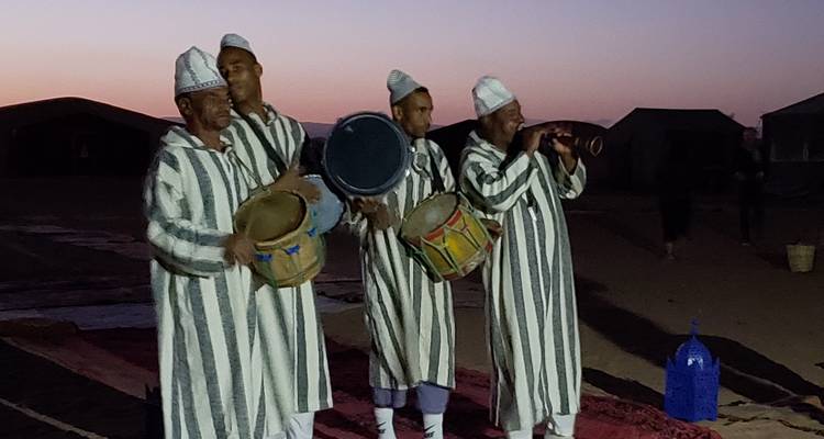 Muzikanten die optreden in traditionele kledij tijdens de schemering.
