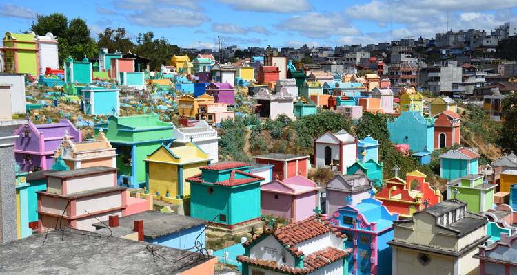 Cimetière sur une colline rempli de tombes peintes de couleurs vives dans toutes les teintes sous un ciel bleu au Guatemala.