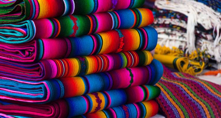 Des piles de textiles guatémaltèques tissés à la main aux couleurs arc-en-ciel, éclatants et vibrants, exposés à un étal du marché.