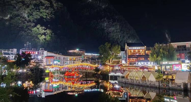 Night cityscape with illuminated shops and water reflections.