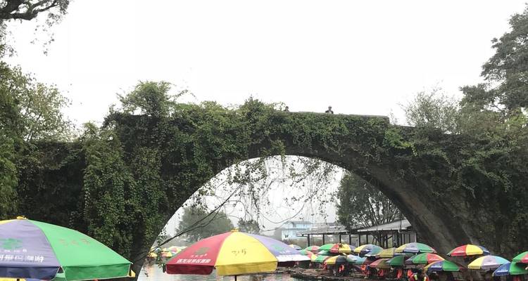 Historic bridge over a river with colorful umbrellas.