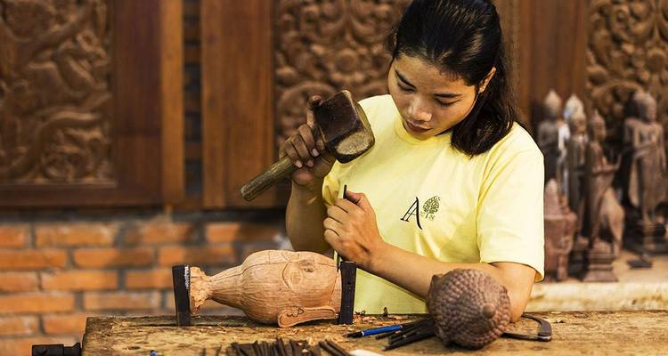 Artisan carving wood in a traditional setting.