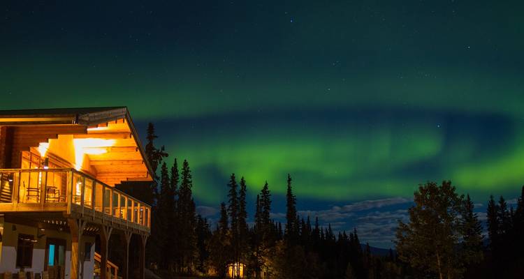 Cabane avec aurores boréales en arrière-plan.