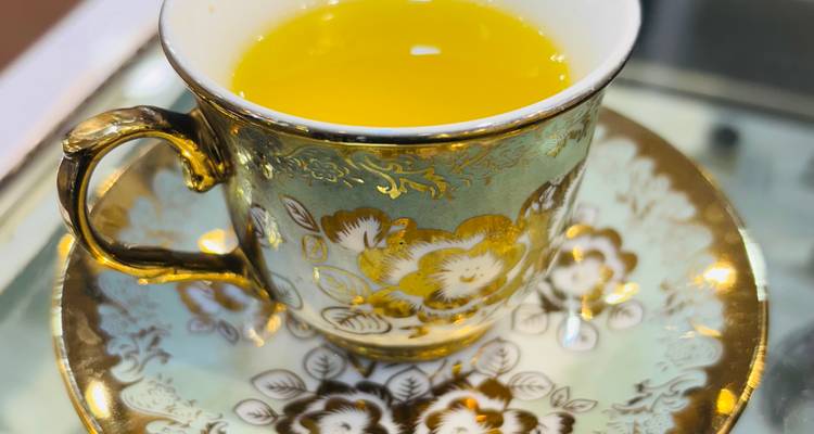 Un gros plan d'une tasse décorative avec un liquide jaune.