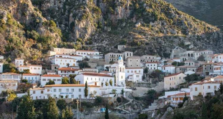 View of a traditional Albanian village against rocky hills.