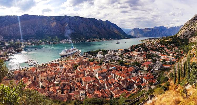 A coastal town with red-roofed buildings and docks with cruise ships.