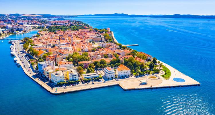 Aerial view of a coastal city with blue waters and historic architecture.