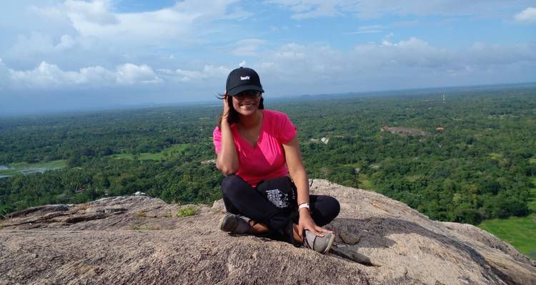 Person sitting on a rock overlooking a vast landscape.