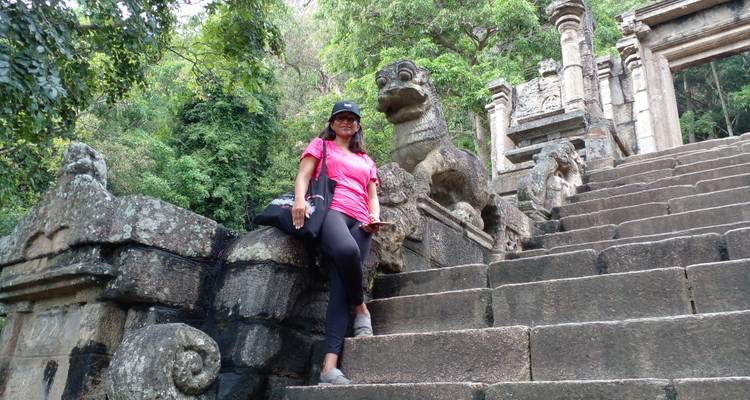 Person standing next to ancient statues on stone steps.