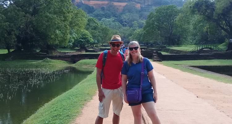 Two people posing on a pathway with greenery.