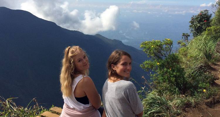 Two people sitting on a mountainside with a scenic view.