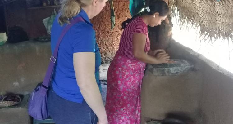 Deux femmes dans une cuisine traditionnelle, l'une préparant de la nourriture.