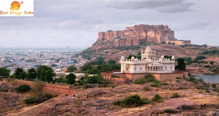 Hilltop fort overlooking a city with a foreground of gardens.