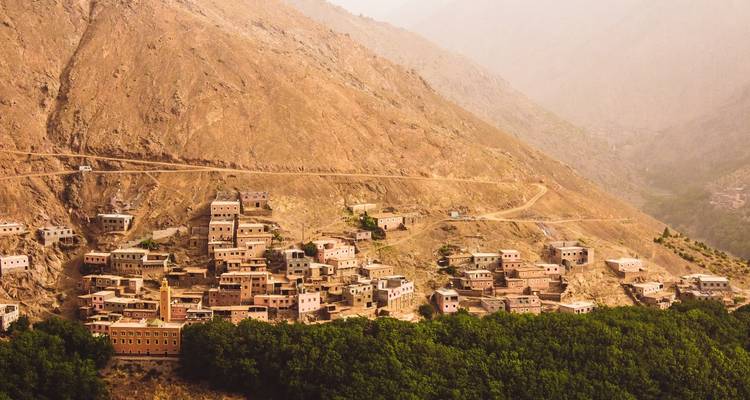 Ein Dorf, das an einem Berghang mit viel Grün erbaut wurde.