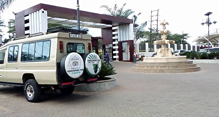 Véhicule de safari garé devant un bâtiment avec une fontaine.