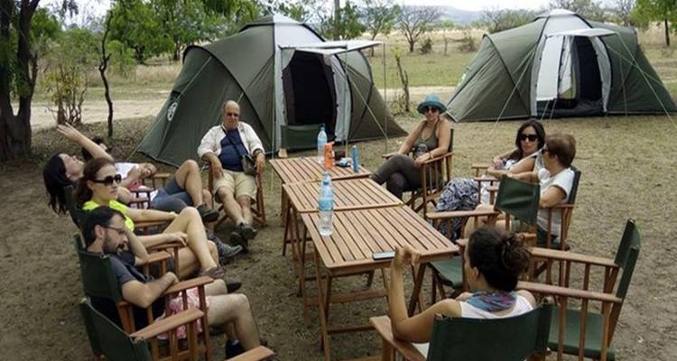 Campeurs se détendant autour d'une table avec des tentes en arrière-plan.