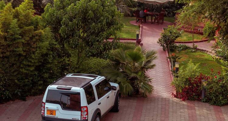 Park with a white car parked in the foreground and outdoor seating in the back.