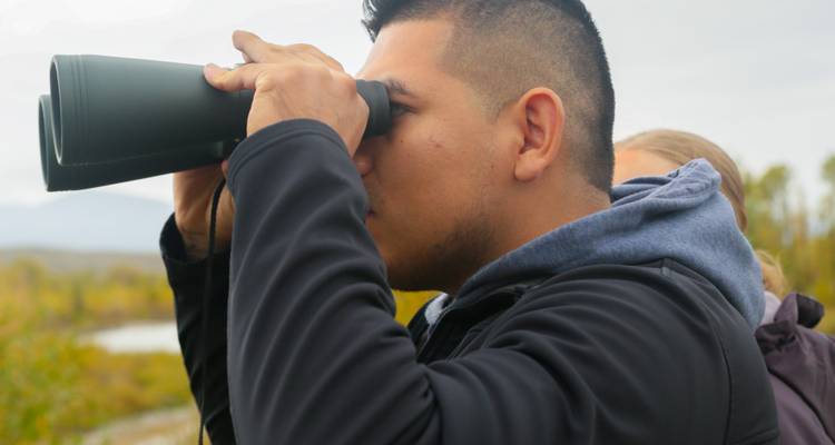 Hombre usando binoculares en un entorno natural.