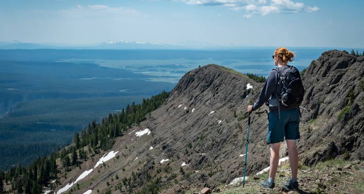 Excursionista en la cima de una montaña contemplando un vasto paisaje.