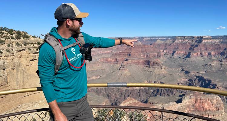 Hombre señalando hacia la vista del Gran Cañón.