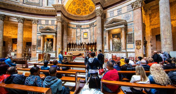Visitors inside a historical building with ornate decoration and a dome ceiling.