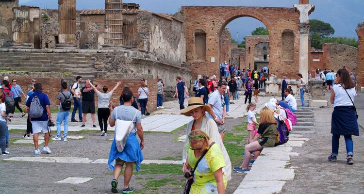 Tourists exploring the ruins of an ancient city with stone structures and arches.