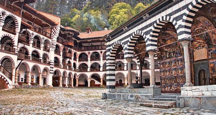 An empty courtyard view of a historic monastery with unique arched architecture.