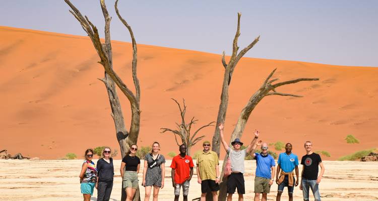 Groep mensen die voor een woestijnduin staat.