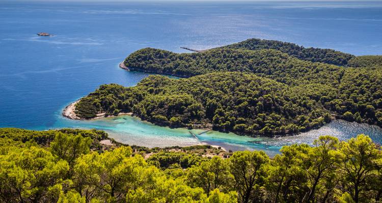 Üppige grüne Insel mit umgebenden türkisfarbenen Gewässern.