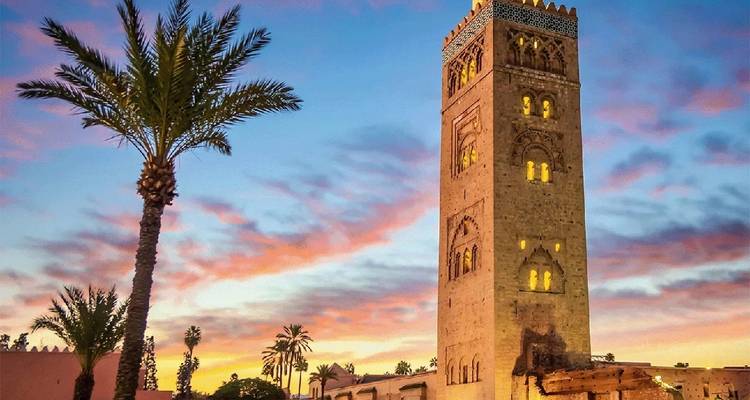 Koutoubia Moskee bij zonsondergang met palmbomen.