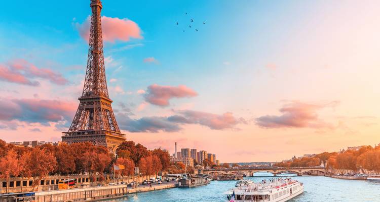 Hermosa puesta de sol parisina sobre la Torre Eiffel y el río con barcos.