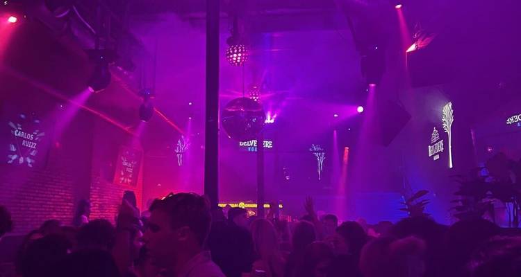 Scène de boîte de nuit avec des lumières colorées et une foule qui danse.