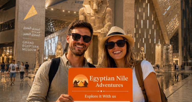 Couple heureux tenant une pancarte Egyptian Nile Adventures dans le hall du Grand Musée égyptien avec de gigantesques statues en arrière-plan.