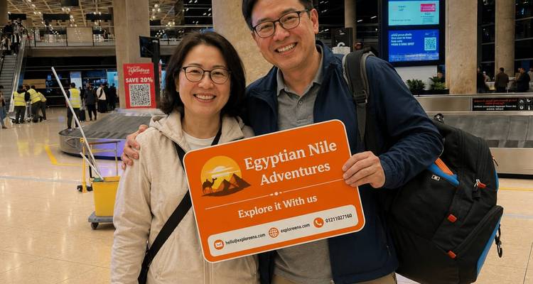 Des voyageurs souriants tenant une pancarte Egyptian Nile Adventures à un carrousel à bagages dans un aéroport.