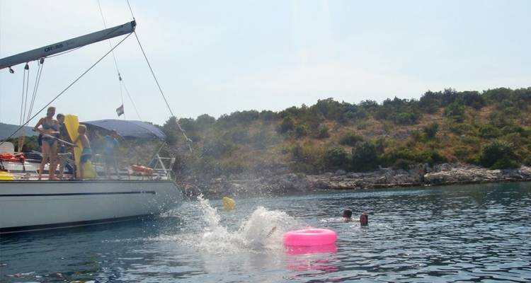 People having fun with a boat and inflatable rings on water.